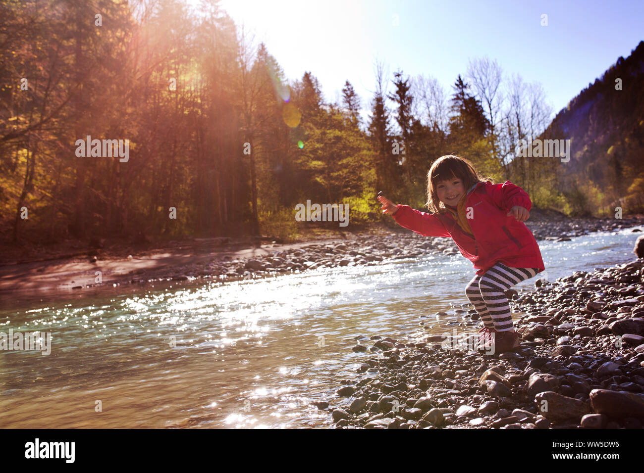5-Jähriges Mädchen in roten Jacke skipping Stones Stockfoto