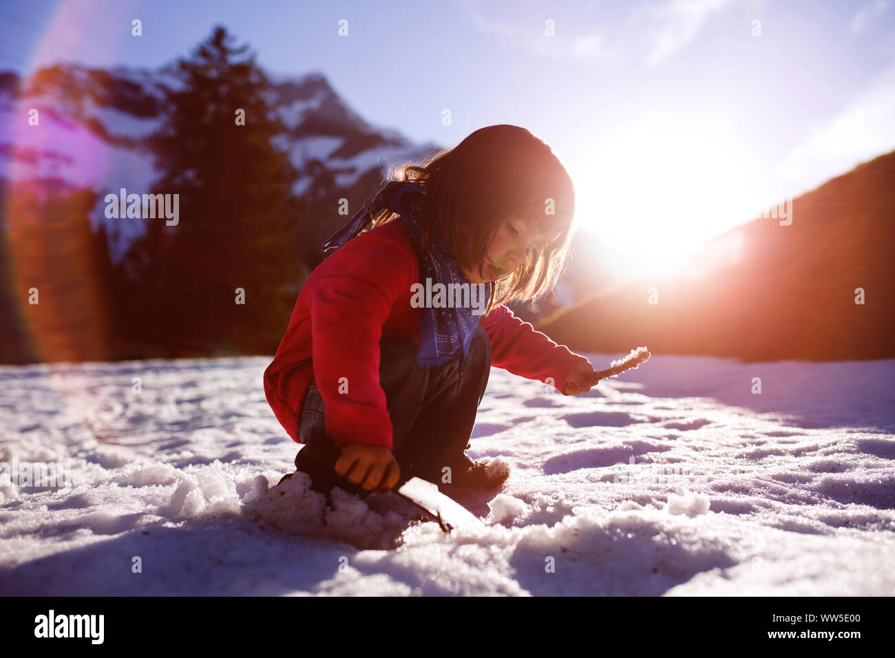 4-6 Jahre altes Mädchen das Graben im Schnee, Sonne, Hintergrundbeleuchtung Stockfoto