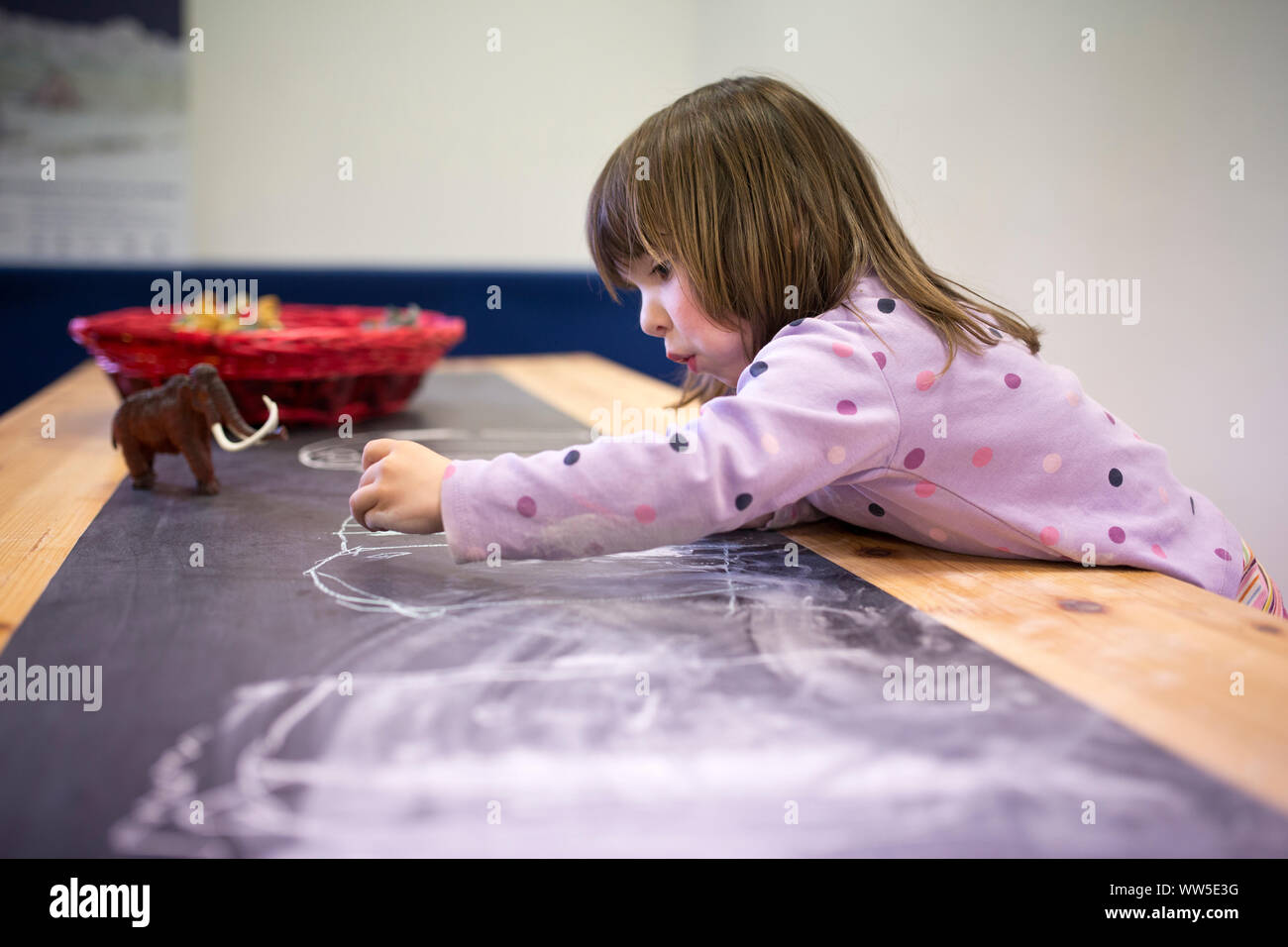 3-6 Jahre altes Mädchen Zeichnen mit Kreide auf eine Tischplatte Stockfoto