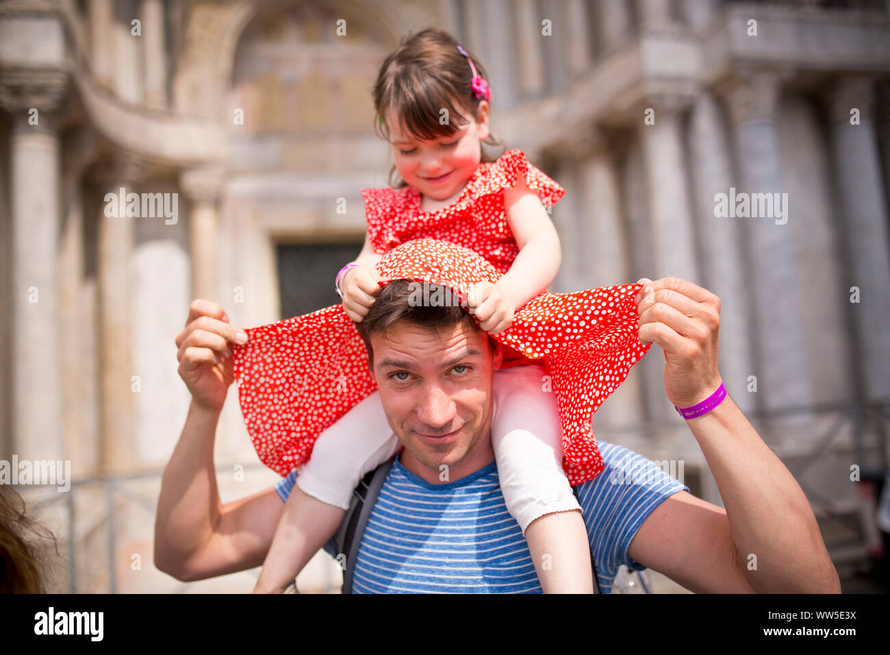 30 bis 40 Jahre alten Vater mit 4-6 Jahre alte Tochter mit roten Kleid sitzt auf den Schultern Stockfoto