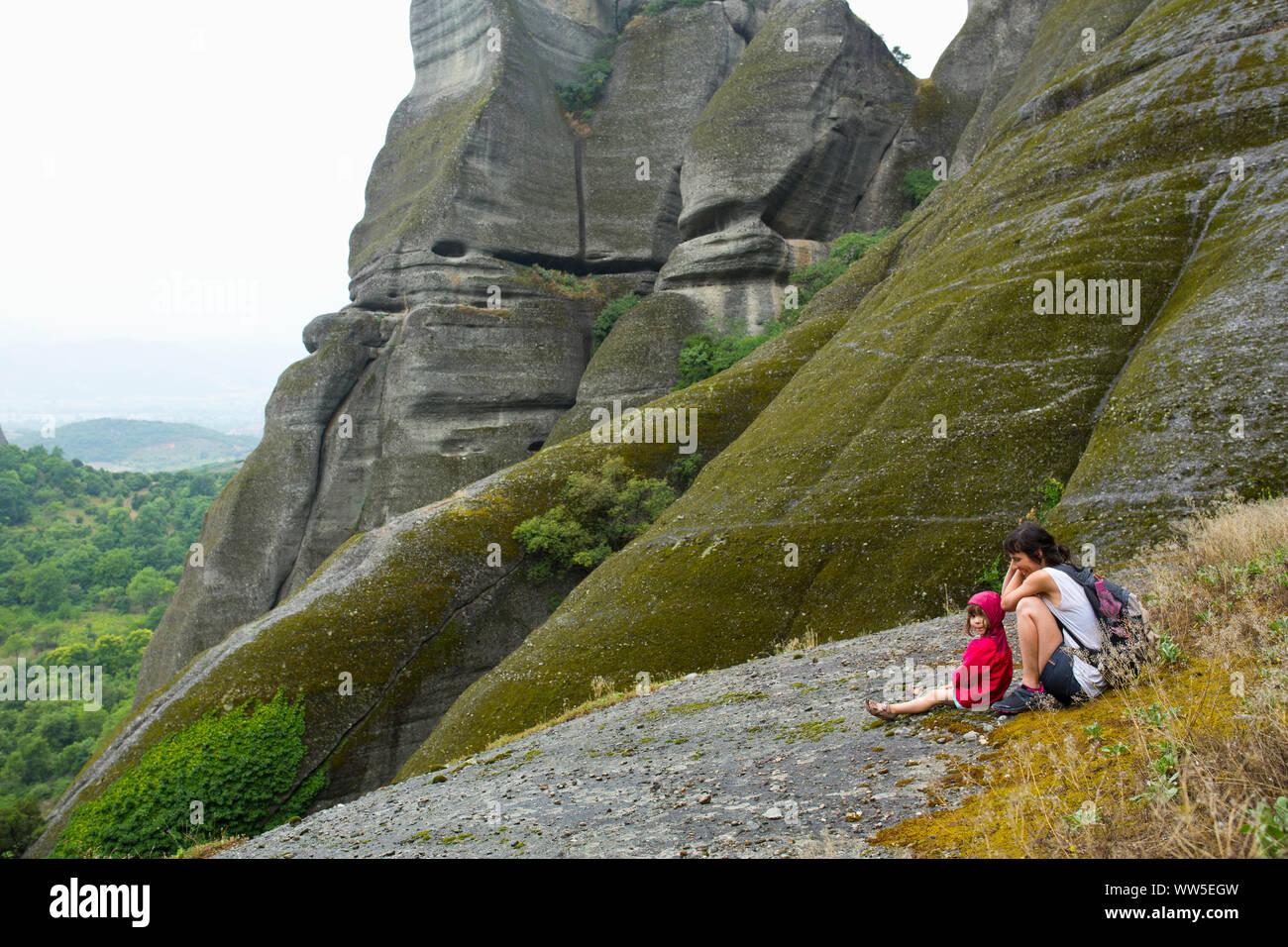 Panoramabild der felsigen Landschaft rund um Meteora mit 30-40 Jahre alten Frau und Kind sitzen auf Leiste Stockfoto