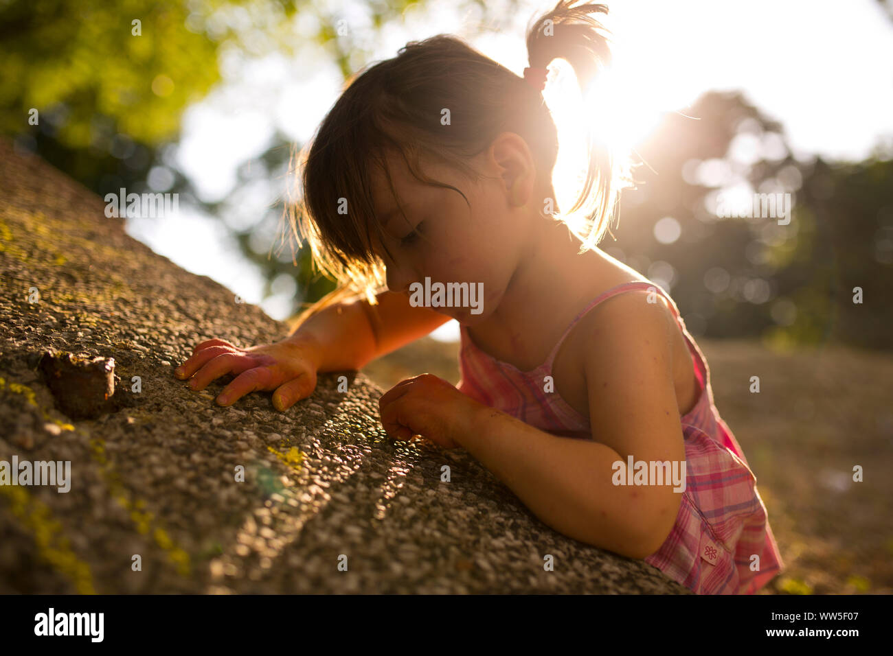 4-6 Jahre altes Mädchen Zeichnen mit Kreide auf graue Wand, Sonne, Hintergrundbeleuchtung Stockfoto