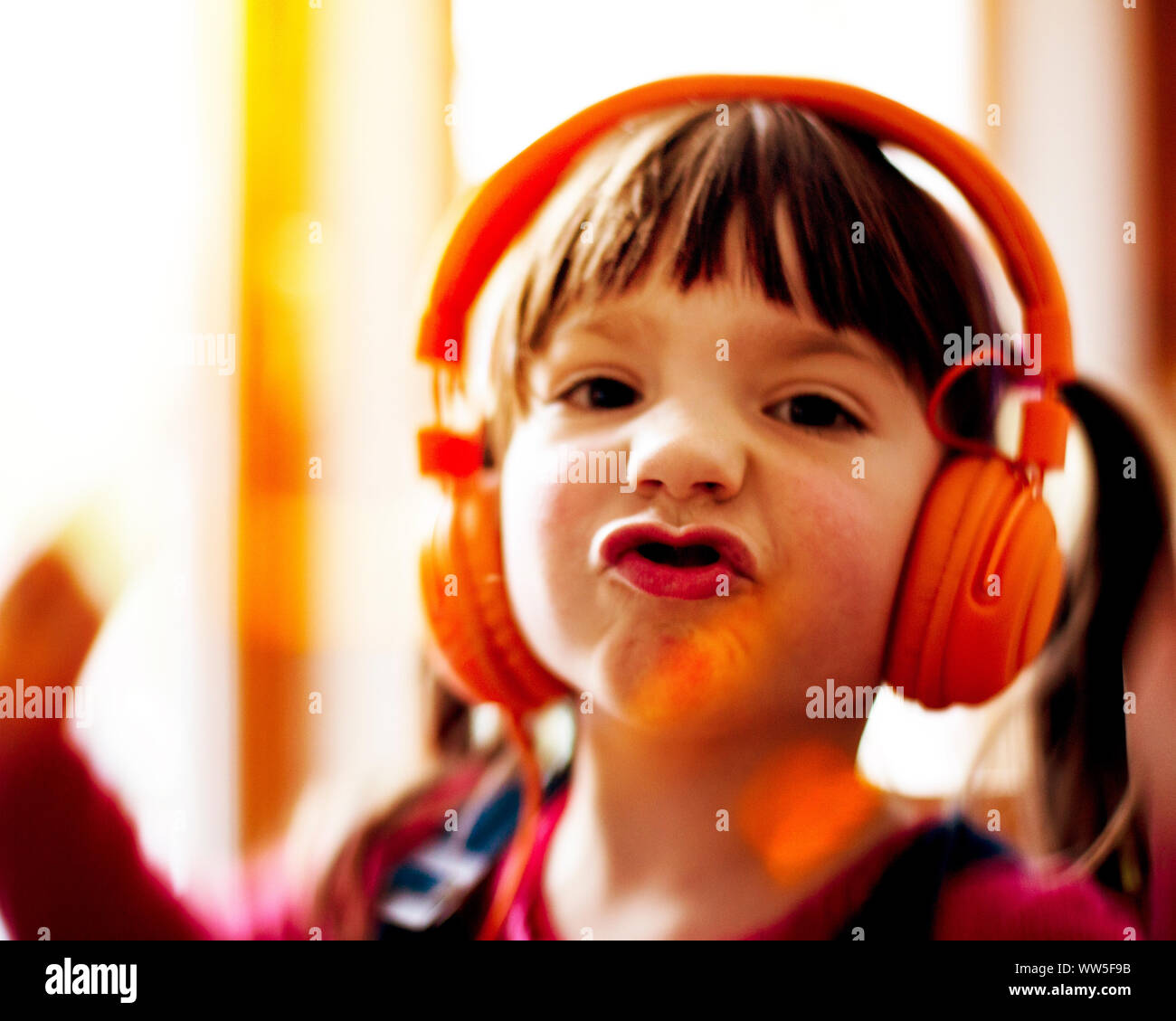 4-6 Jahre altes Kind tanzen mit orange Kopfhörer, Mimik, Porträt Stockfoto
