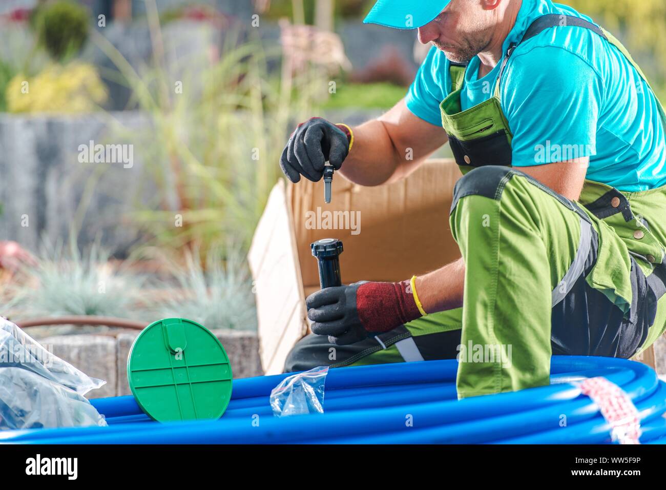 Professionelle Gartenbewässerung Gebäude. Kaukasische vierzig Jahre alten Gärtner Kontrolle für das System. Automatische Bewässerung. Stockfoto