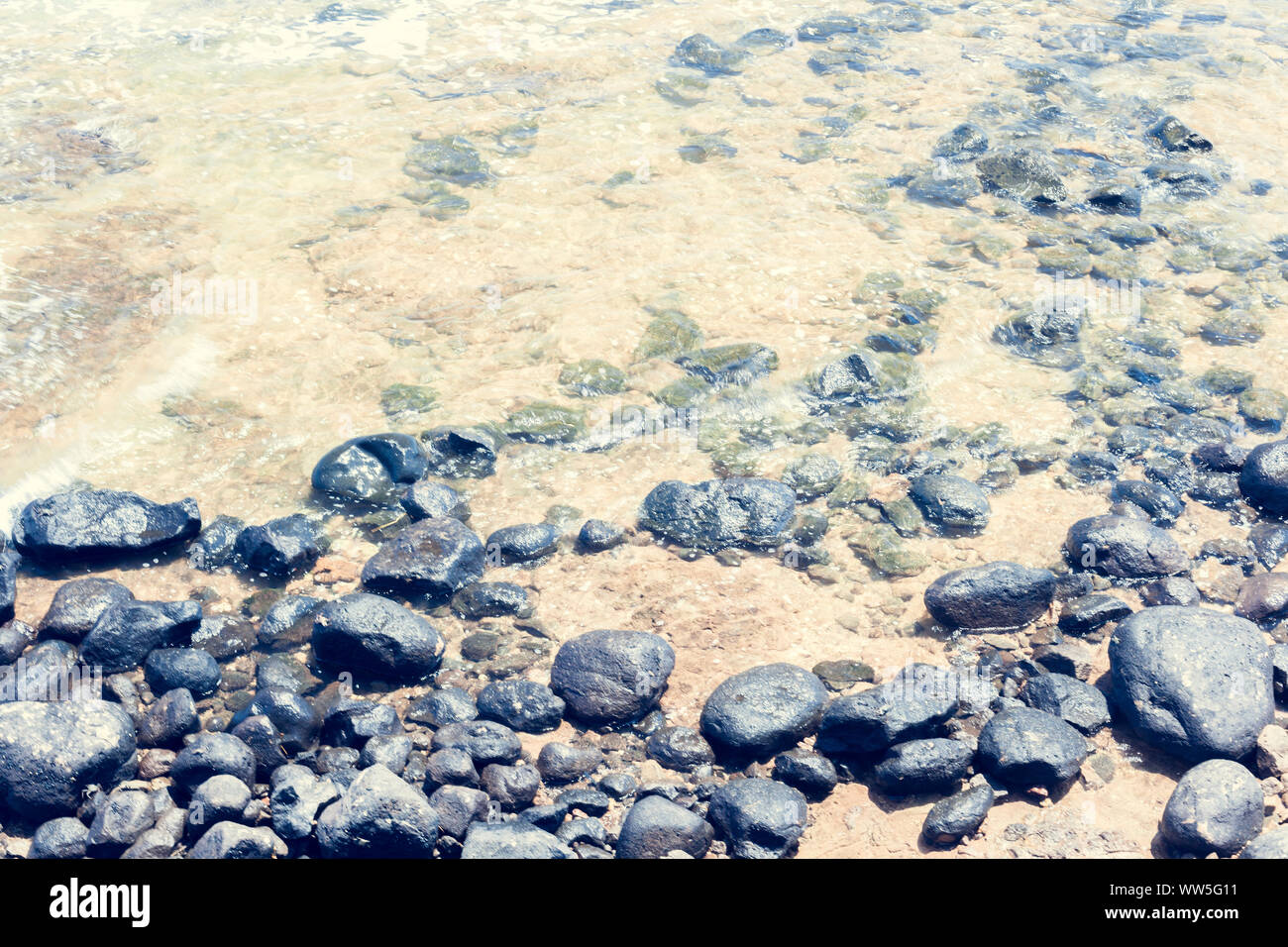 Steine am Meer am Strand, Kauai, Hawaii, USA gebadet Stockfoto