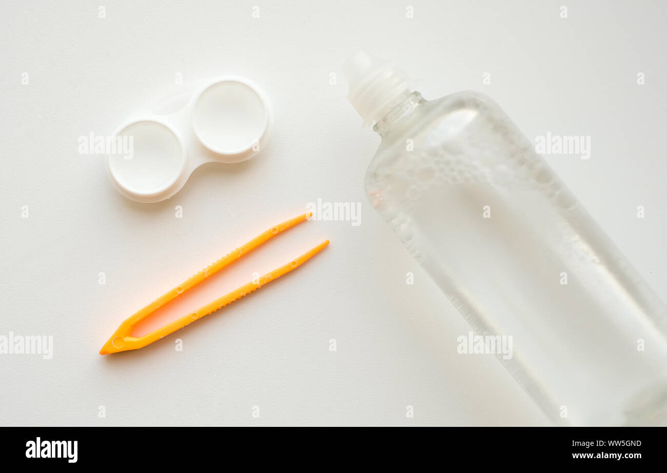 Zubehör für die richtige Verwendung von Kontaktlinsen: Gehäuse, Pinzette und Flasche Lösung auf weißem Hintergrund. Sichere Sehkorrektur. Blick von oben. Stockfoto