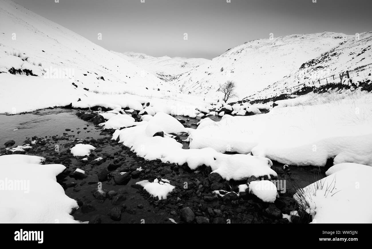 Ein schwarz-weiß Bild von einer verschneiten Winter Lake District Szene von Hayeswater Gill in der Nähe von hartsop im Lake District. Stockfoto