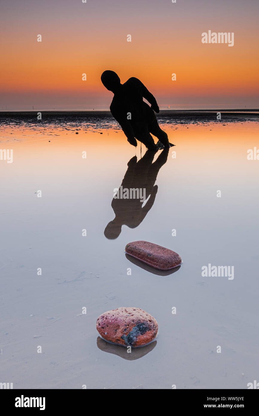 Antony Gormley Gusseisen Statuen, Bestandteil der Installation benannt "Woanders", am Strand von Crosby in Sefton bei Sonnenuntergang. Stockfoto