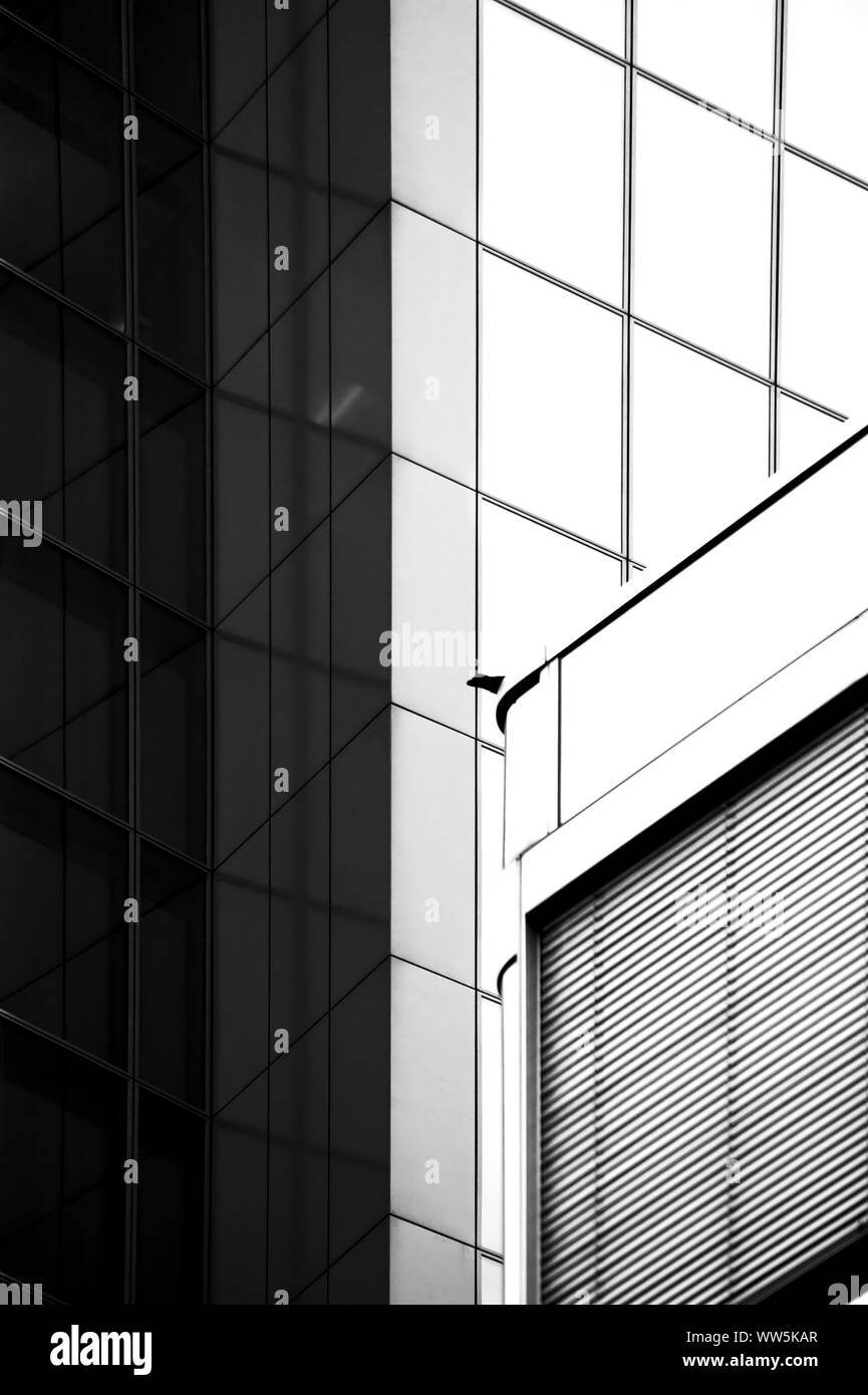 Die Schwarz-Weiß-Fotografie von der Dachkante eines modernen Gebäudes und die Fassade eines anderen Hauses, Stockfoto