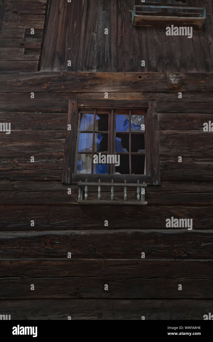 Zerbrochene Fensterscheiben, die am alten Holz- Haus Stockfoto