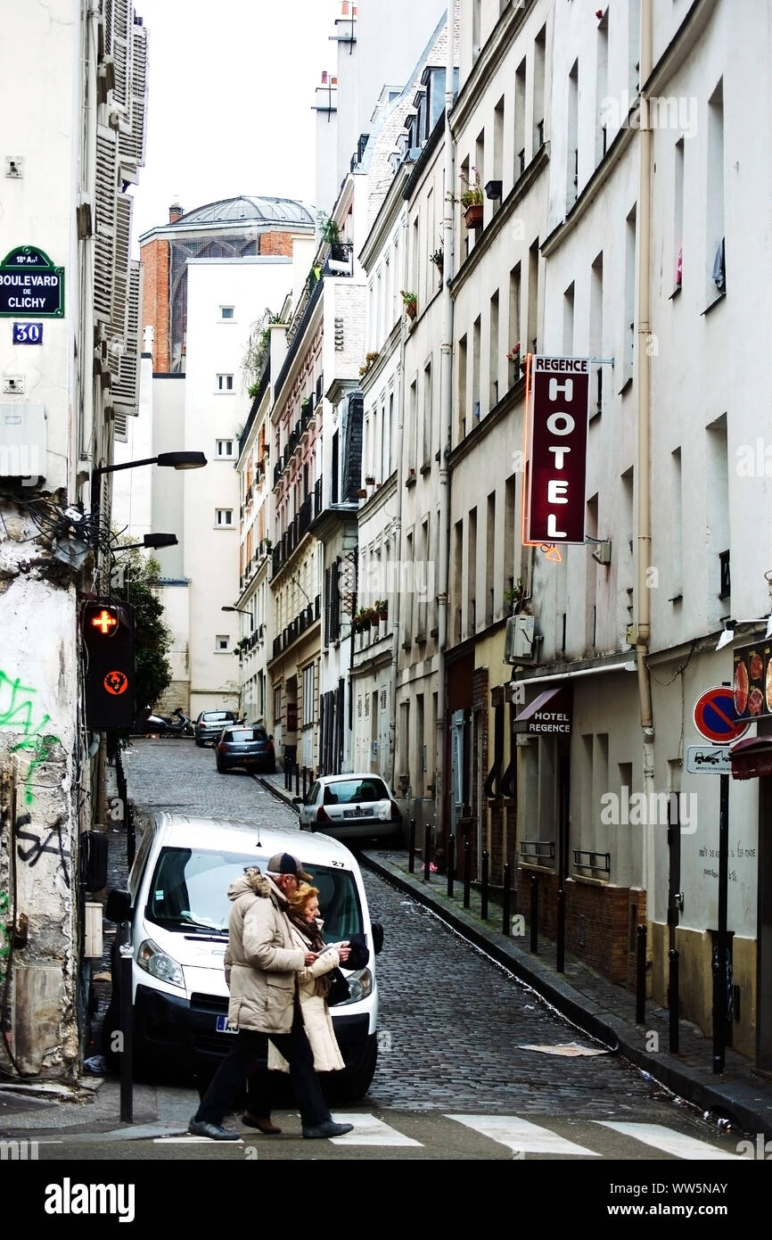 Zwei alte Leute, die eine Seitenstraße mit einer Ampel und ein Hotel im Bezirk Montmartre in Paris, Stockfoto