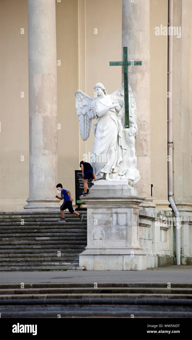 Kinder spielen an der Treppe der Eingang der Kirche von St. Karl in der Skulptur ein Engel in Wien, Stockfoto