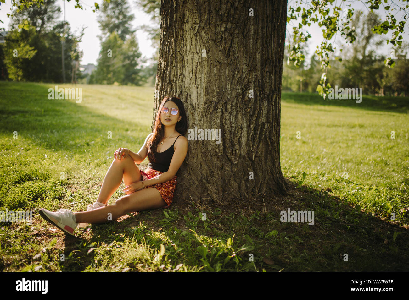 Frau sitzt unter einem Baum im Park, Serbien Stockfoto