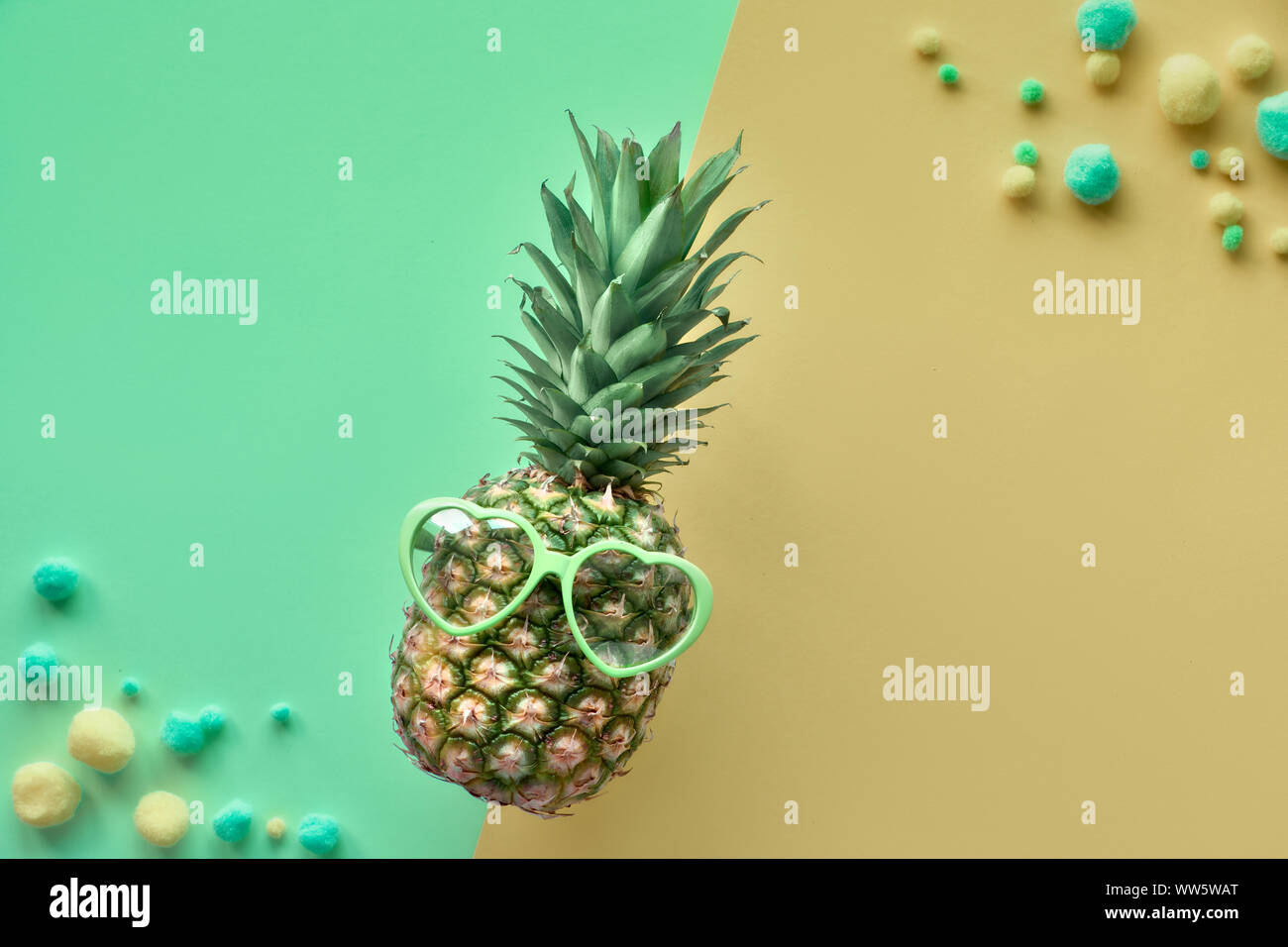 Lustige Ananas in Sonnenbrille, flach auf Split neo Minze und khaki Papier Hintergrund Stockfoto