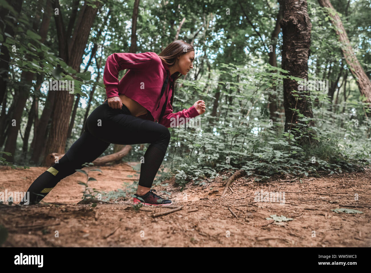 Seitenansicht eines junge sportliche Mädchen überwindet steile für die Ausbildung in den Wald klettert. Volle Länge geschossen von einer selbstbewussten weiblichen Athleten Klettern ein Wald tr Stockfoto