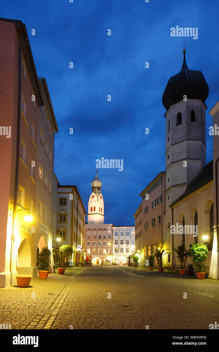 Stadt Pfarrkirche St. Nikolaus auf dem Max-Josefs-Platz links, Heiligen Geist Kirche auf der rechten Seite, Heiliger Geist Straße, historische Wohnhäuser und Gewerbebauten in der Dämmerung, Rosenheim, Oberbayern, Bayern, Deutschland, Europa Stockfoto