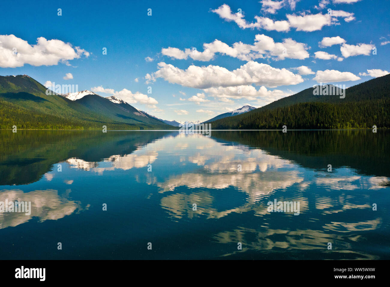 Berglandschaft mit See, weiße Wolken im Wasser spiegeln, Bowron Lake Provincial Park, British Columbia, Kanada Stockfoto