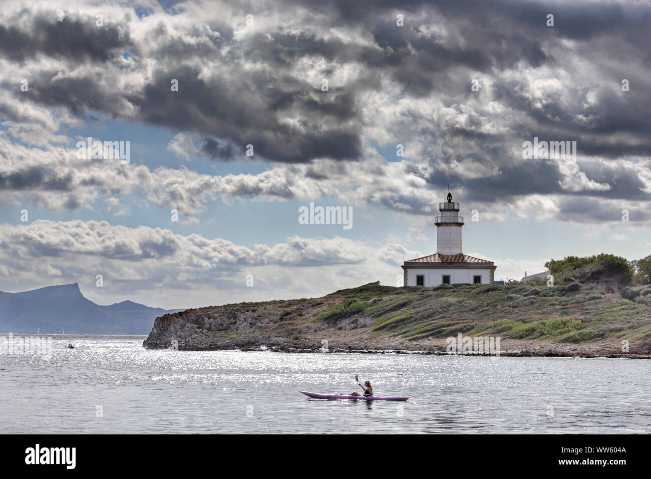 Spanien, Mallorca, Alcanada, Faro de Alcanada, Leuchtturm, Tretboot, Frau, Meer, Himmel, Wolken, Hintergrundbeleuchtung, kein Modell Release Stockfoto