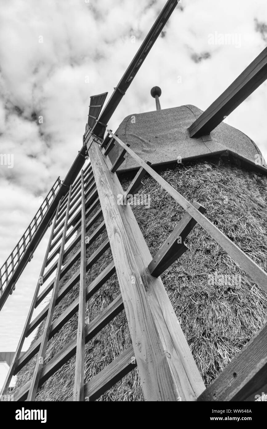 Cloud-bedeckten Himmel mit einer kleinen alten strohgedeckten Windmühle, b/w Stockfoto