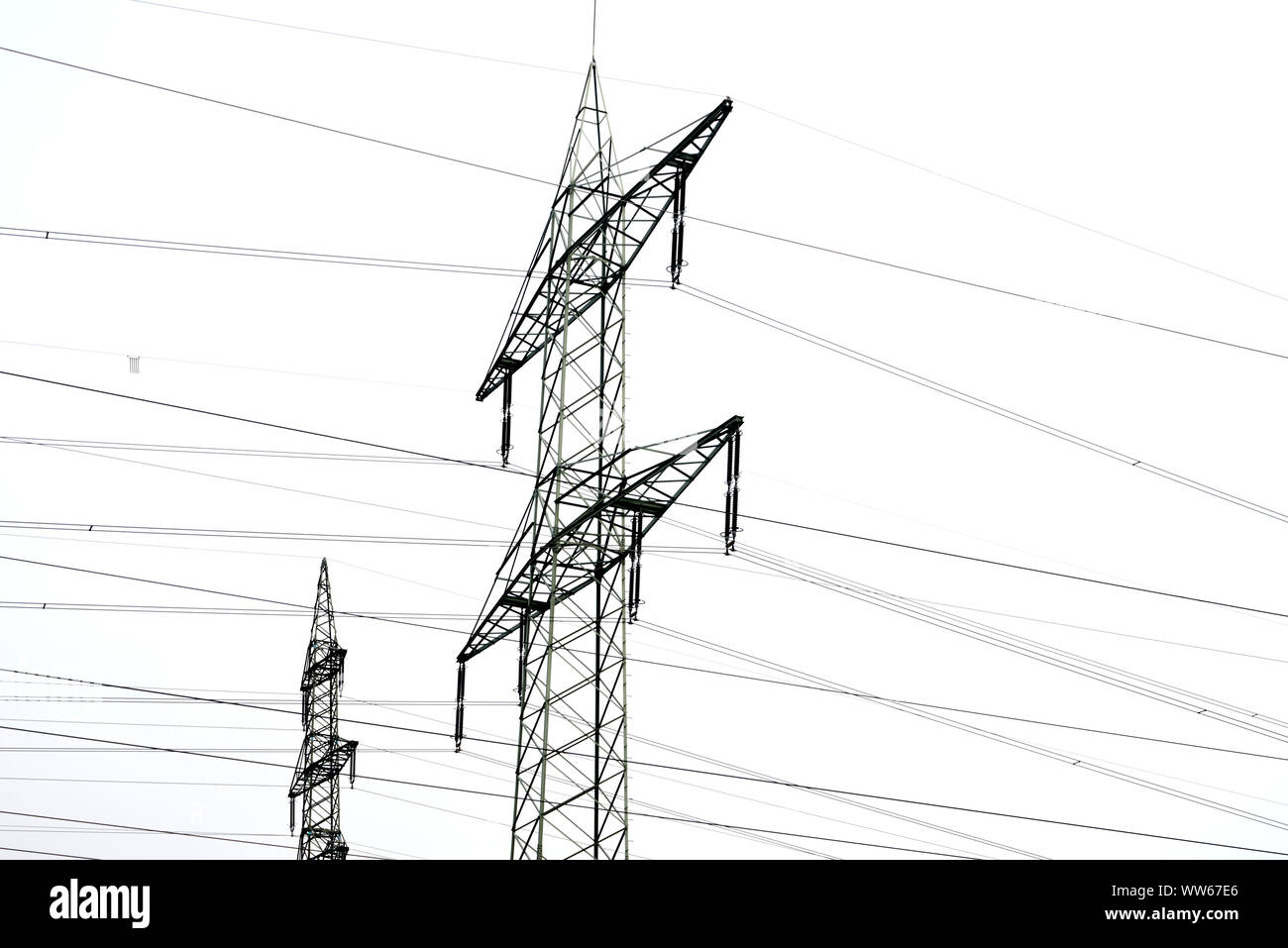 Strommast mit Versorgungsleitungen vor weißen Himmel Stockfoto