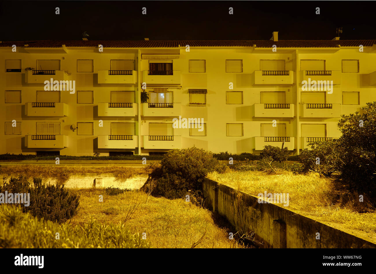 Appartementhaus, in der Nacht, Fassade, Balkon und Fenster, Straße, gelbes Licht Stockfoto