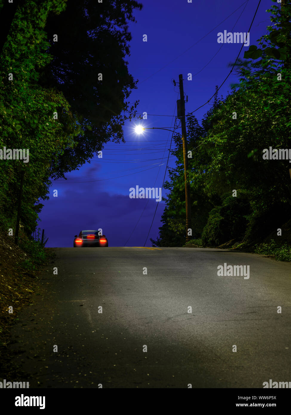 Einsames Auto, das bei Nacht auf dem steilen Hügel fährt, Pennsylvania, USA Stockfoto