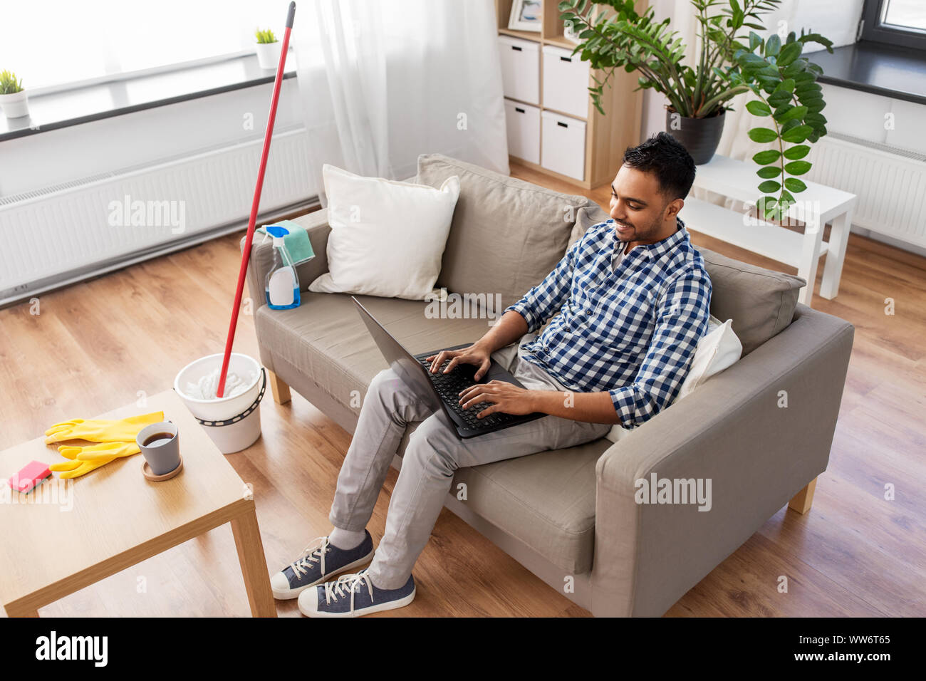 Mann mit Laptop nach Hause Reinigung Stockfoto