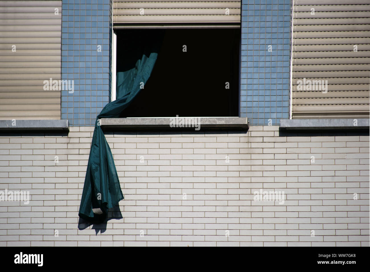 Ein Durchhang Vorhang weht aus dem Fenster eines clinkered Wohnhaus, Stockfoto