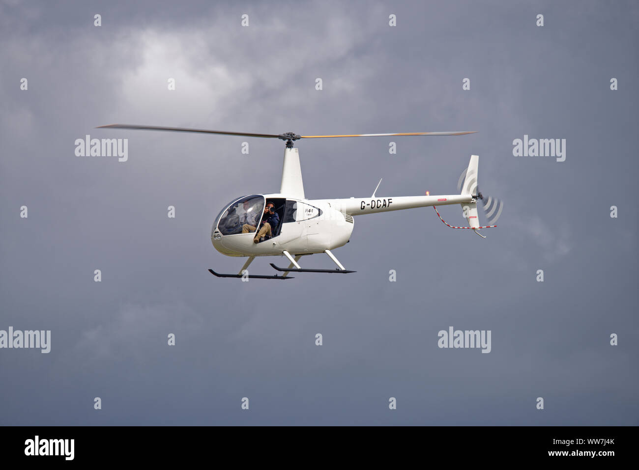 Fotograf saß in der offenen Tür des Robinson R44 G-OLAF Leichter Hubschrauber photograping bei der RIAT Stockfoto