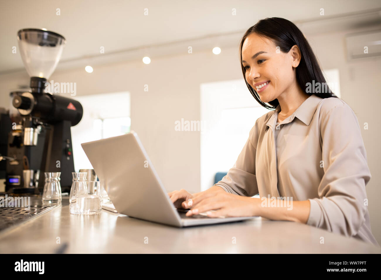 Junge glücklich weibliche Unternehmer durch Arbeitsplatz vor Laptop Stockfoto