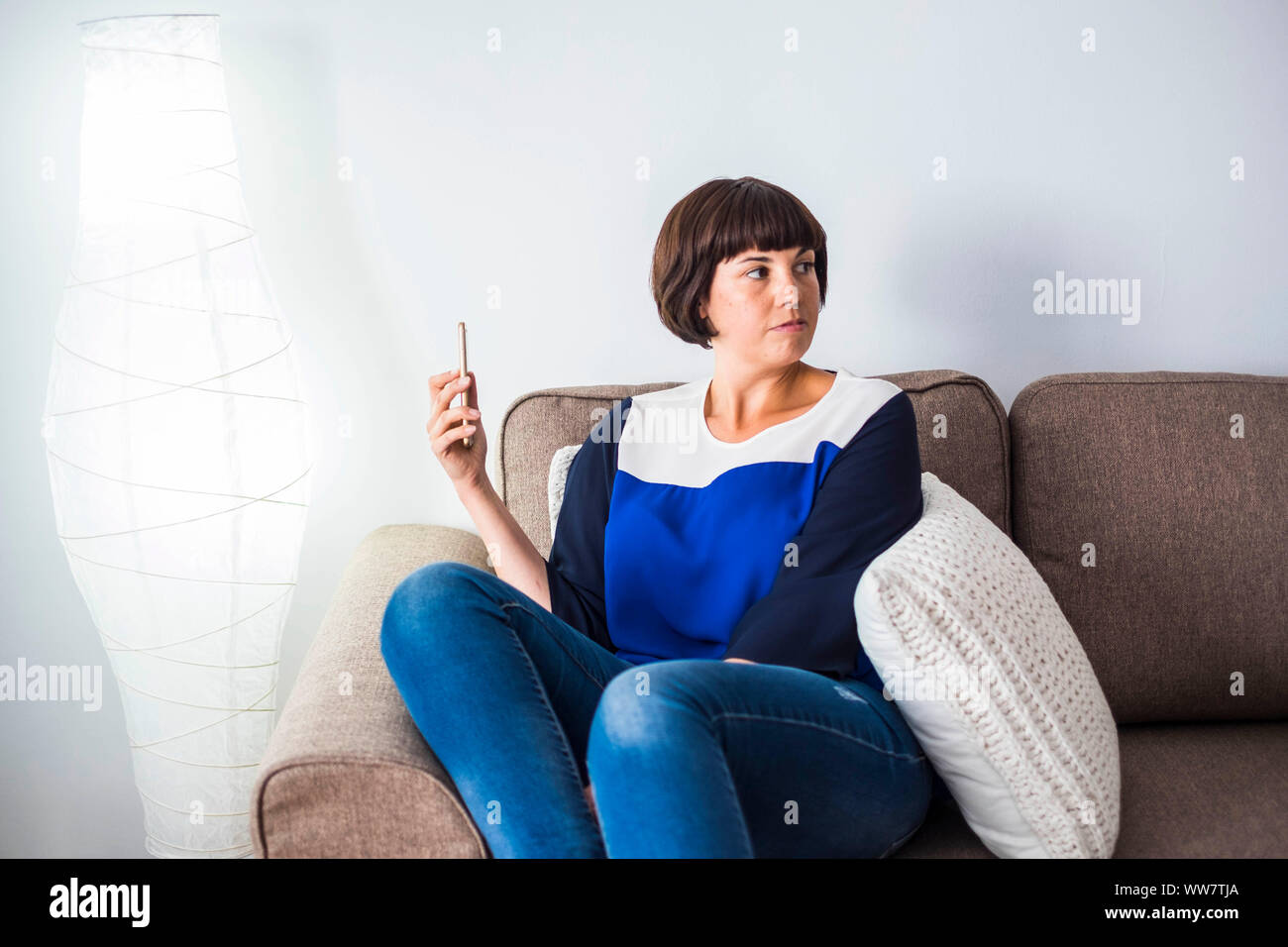 Technologie zu Hause mit schönen jungen schwarzen Haar Frau sitzen Sie zu Hause mit dem Handy. elegantes Haus innen für Lifestyle täglich Szene. Stockfoto