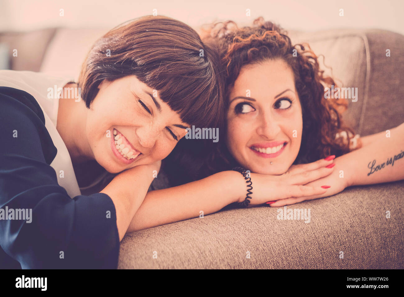 Schöne Zeit und Glück mit Lachen und Lächeln für zwei kaukasischen Freunde zusammen auf dem Sofa zu Hause. Freundschaft Konzept für innen Bild mit Fenster Tageslicht Stockfoto