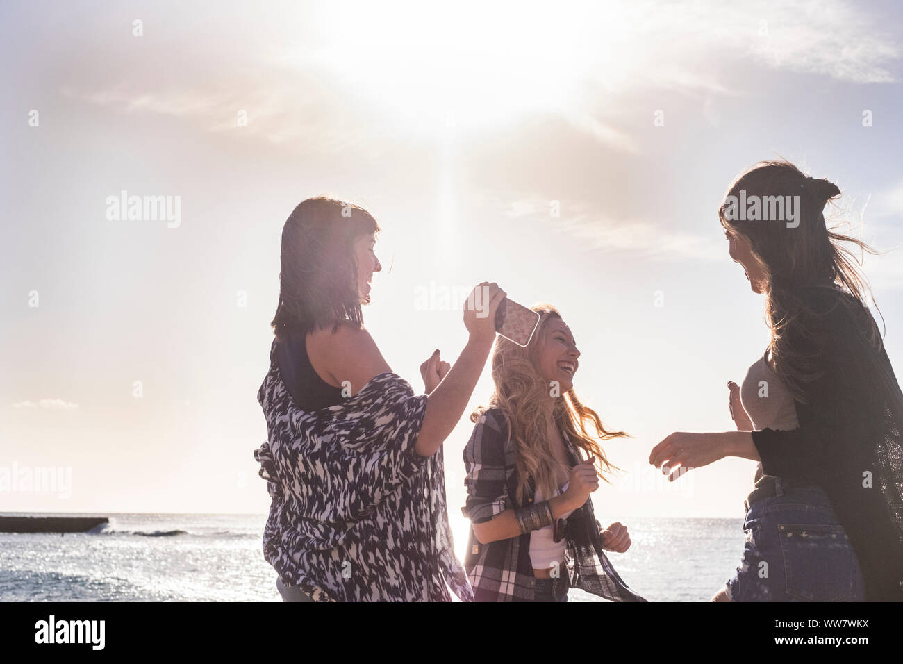 Beziehung zwischen drei junge Schönheit Frau tanzen am Strand während der Ferien. Sonnenuntergang auf Teneriffa, flare Effekt und warm Filter. Stockfoto