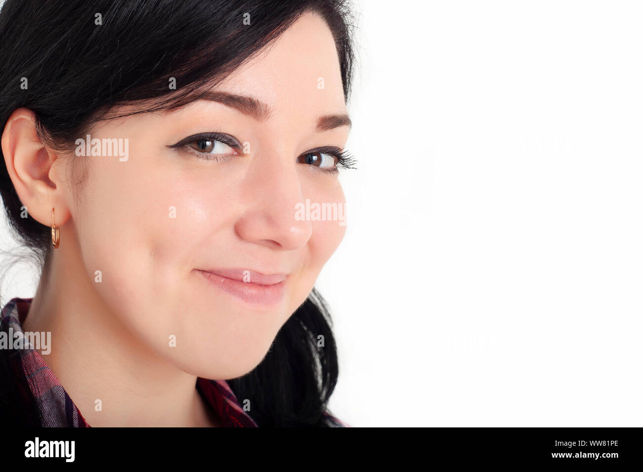 Ein junges fröhliches schönes Brünette Mädchen mit niedlichen Grübchen auf ihren Wangen lächelt und schaut mit Glück in ihren Augen auf die Kamera. Weißer Hintergrund. Stockfoto