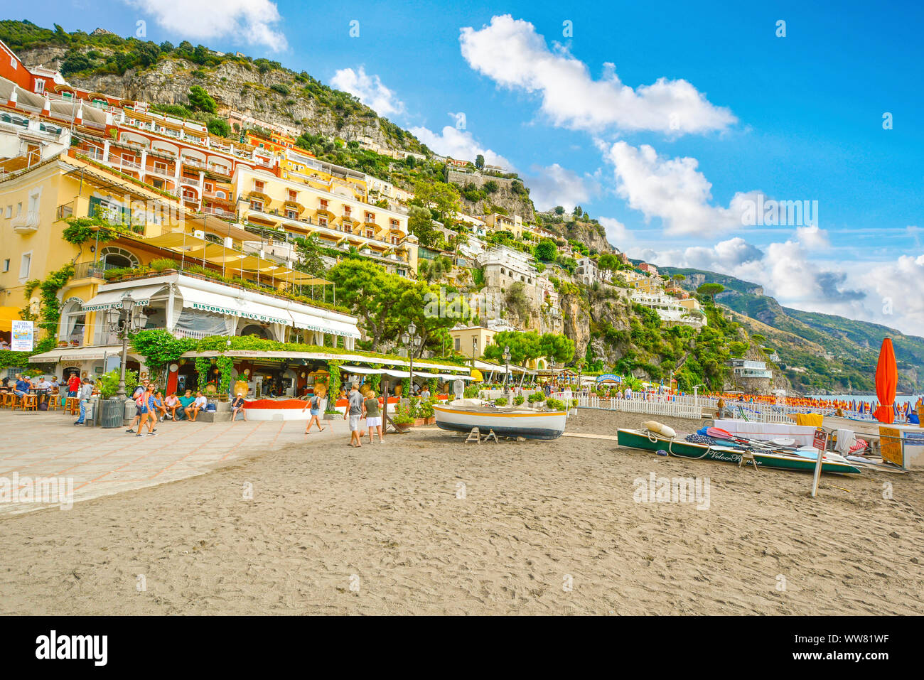 Touristen genießen den Sandstrand, Restaurants, Resorts und Promenade an der Küste Hügel Stadt Positano, Italien an der Amalfi Küste. Stockfoto