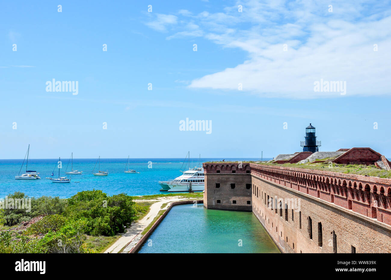 Blick von Fort Jefferson Dach mit Ziegeln, Wasser, Segelboote und Leuchtturm in Dry Tortugas National Park, historische Militärgelände, Florida. Stockfoto