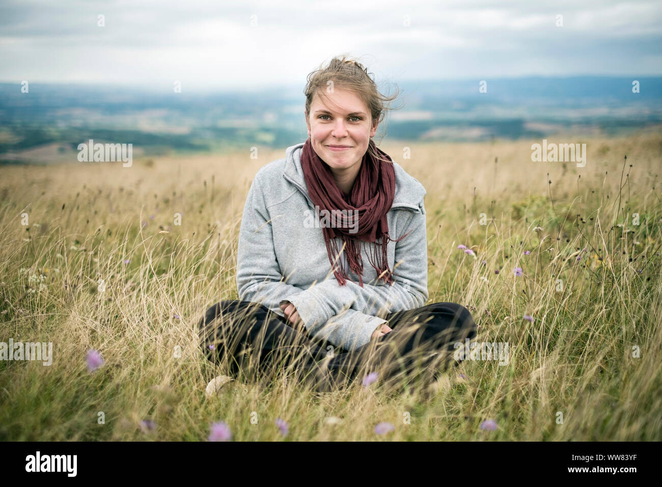 Junge Frau sitzt im Gras Wiese auf Kamera, Revel, Tarn, Frankreich Stockfoto