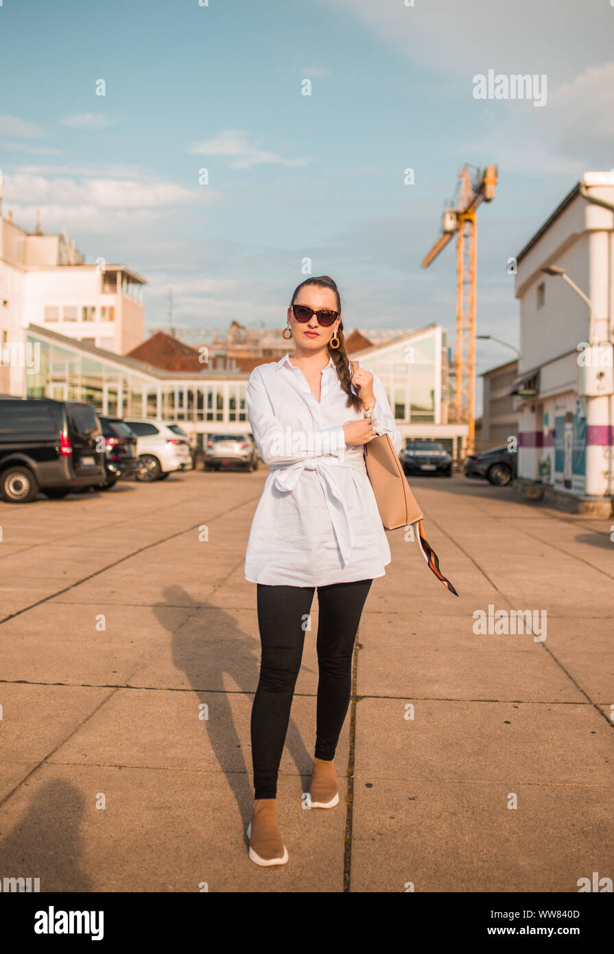 Junge Frau auf dem Bürgersteig holding Tasche Stockfoto