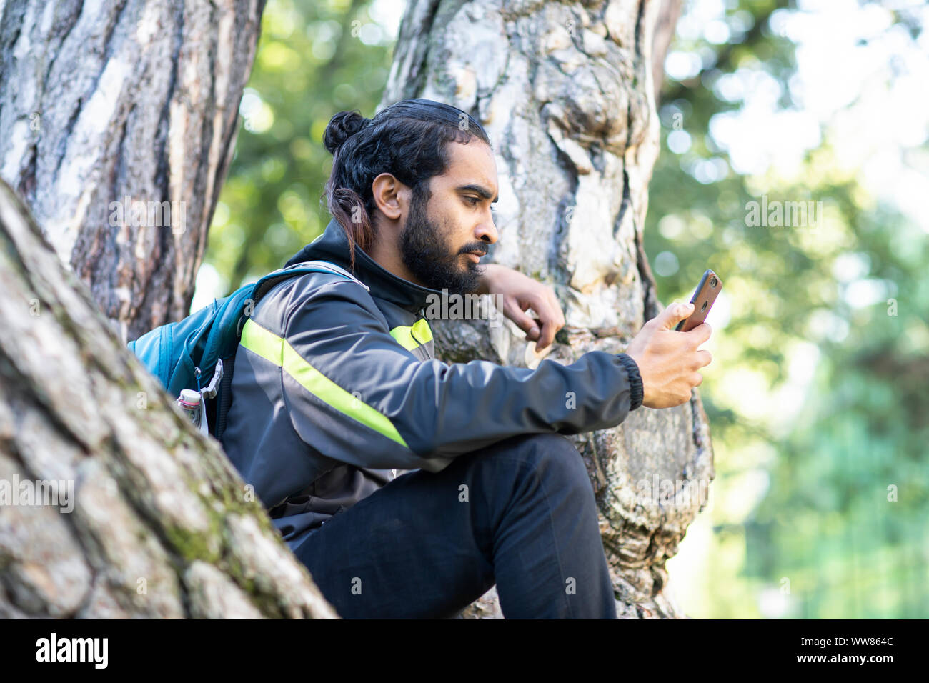 Junge Wanderer Indien sitzen und Kontrolle smart phone Stockfoto
