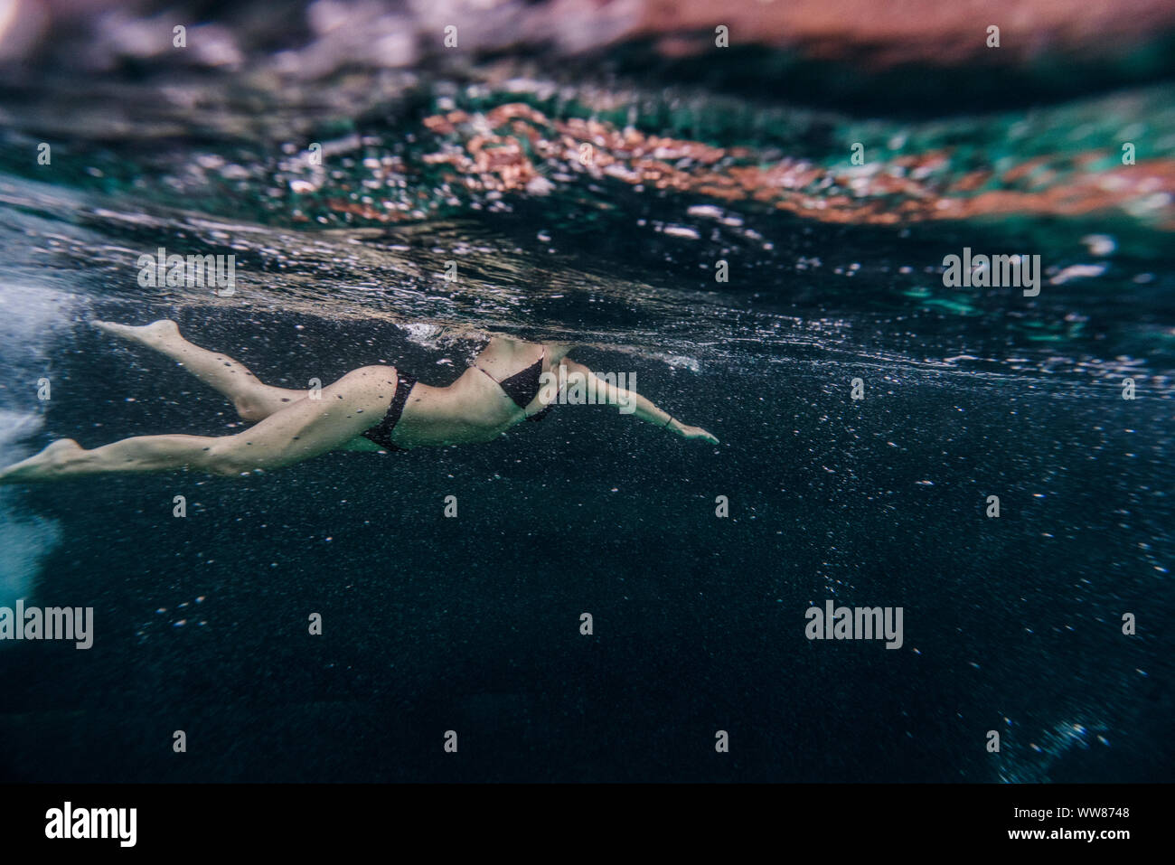 Volle Länge des Frau Schwimmen unter Wasser in der Nähe von einem alten Boot Stockfoto