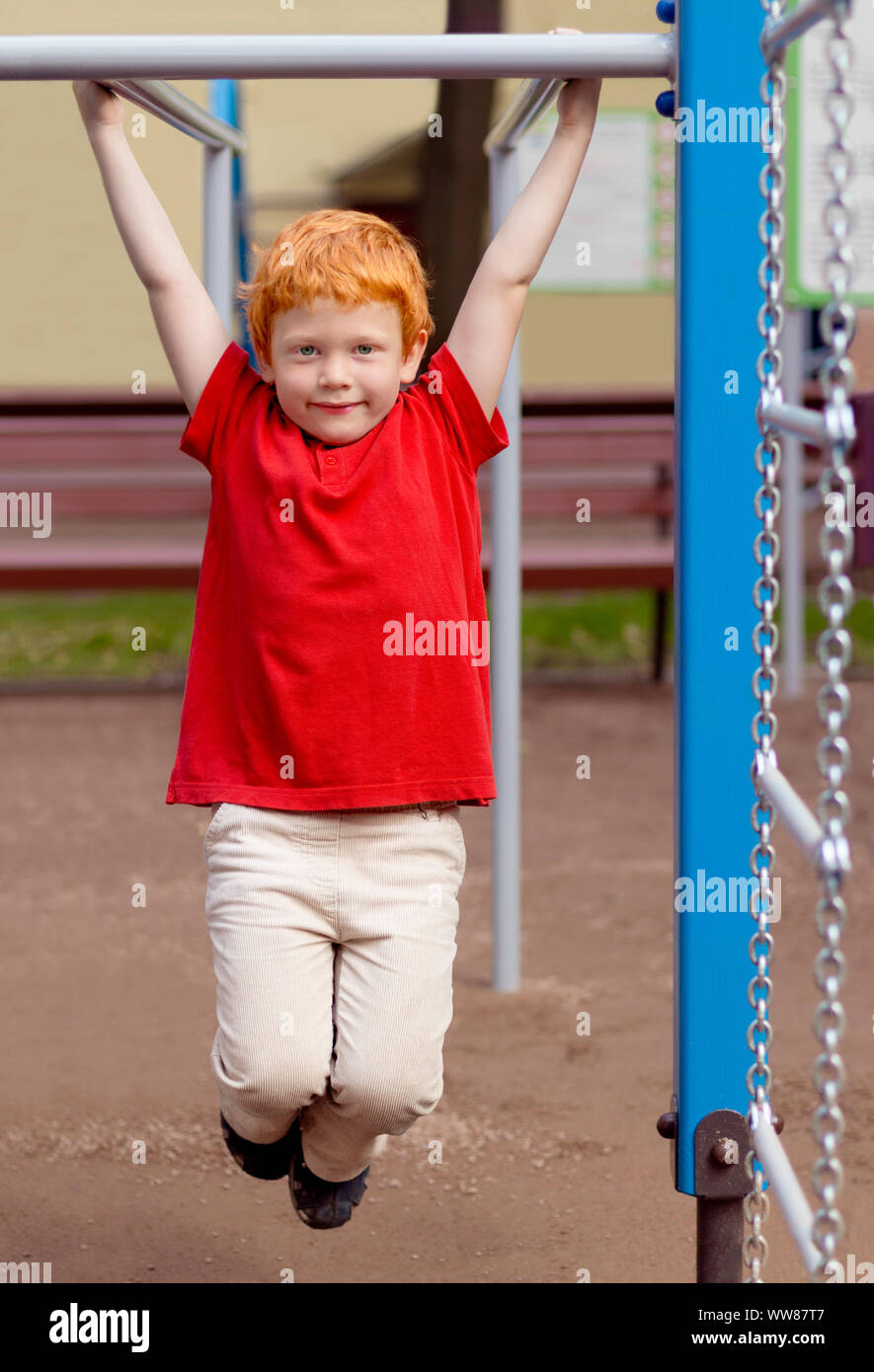 Junge auf Monkey Bars. Little Boy hängen an Gym activity center von Schule Spielplatz. Aktivität im Freien für die Kinder. Sport. Fashion Kid. Cute boy im Sommer Stockfoto