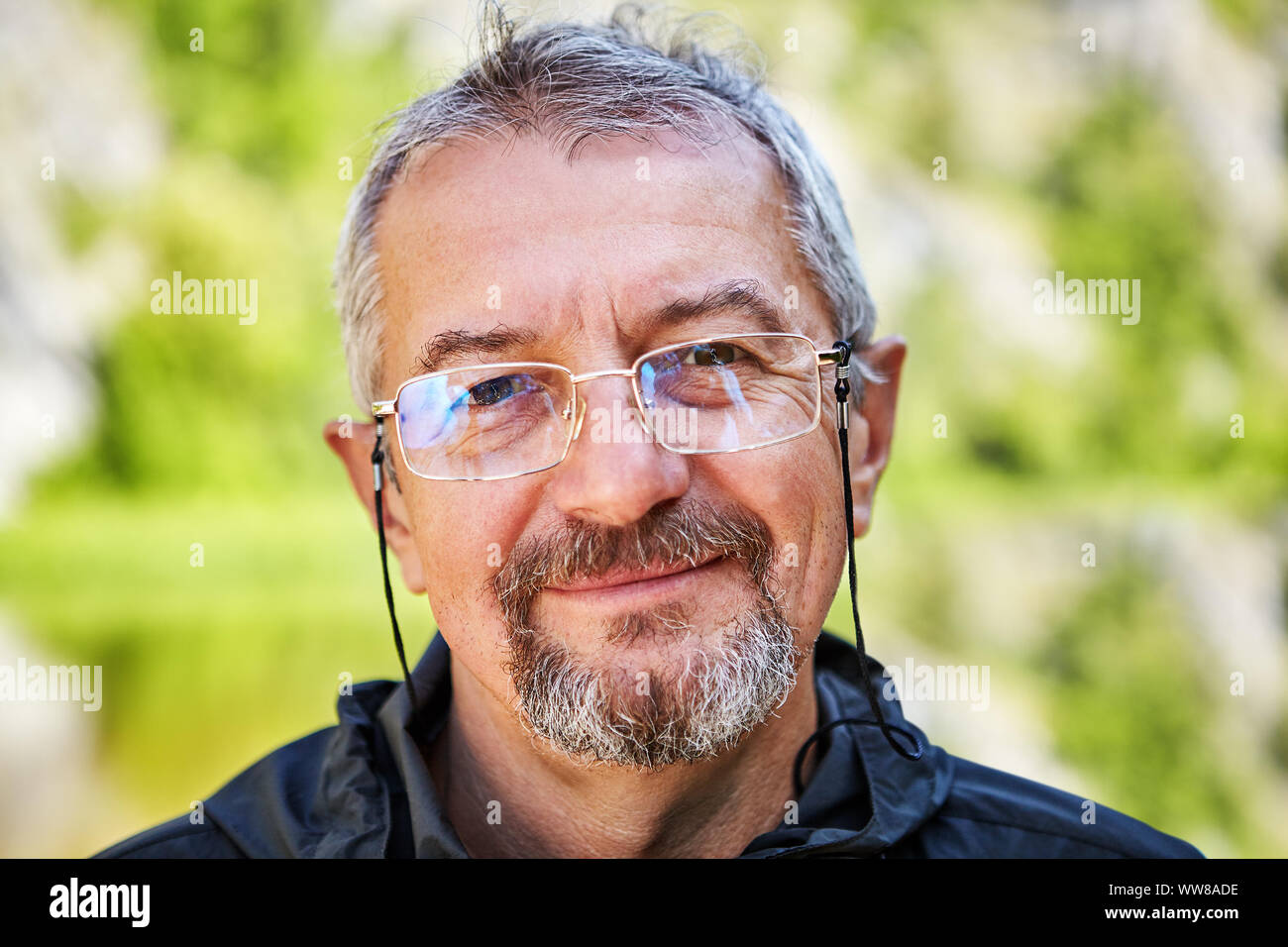 Close-up Gesicht eines lächelnden Mann, 56 Jahre, Brille mit einem dünnen Metall Rahmen und eine elegante Spitze für Sicherheit, ein Mann trägt einen Schnurrbart und Bart, Stockfoto