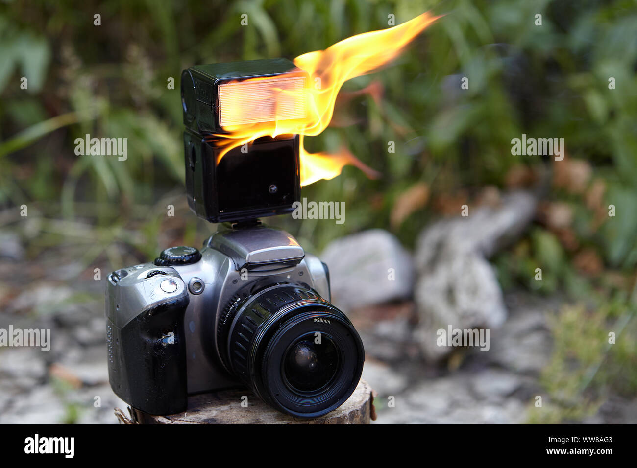 Digitale SLR-Kamera mit Zoomobjektiv und einem brennenden elektronische  Kamera Blitz. Flammen auf der Flash digitale Single-Lens Reflex Kamera  gegen die Bac Stockfotografie - Alamy