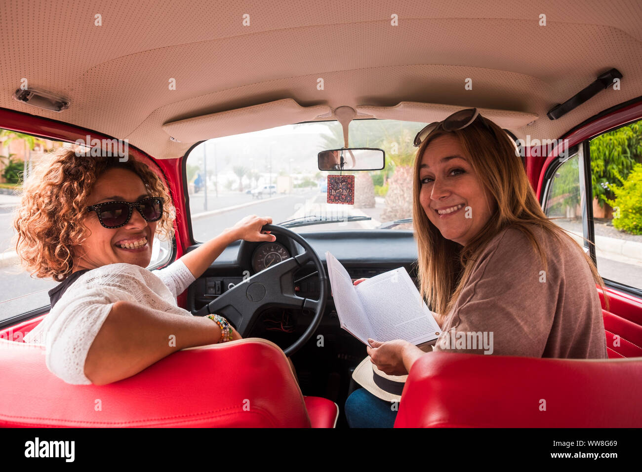 Paar der kaukasischen mittleren Alter Frau in Outdoor Freizeitaktivitäten Aktivität in der Nähe von und sitzen auf einem roten Oldtimer bereit zu reisen, Stockfoto