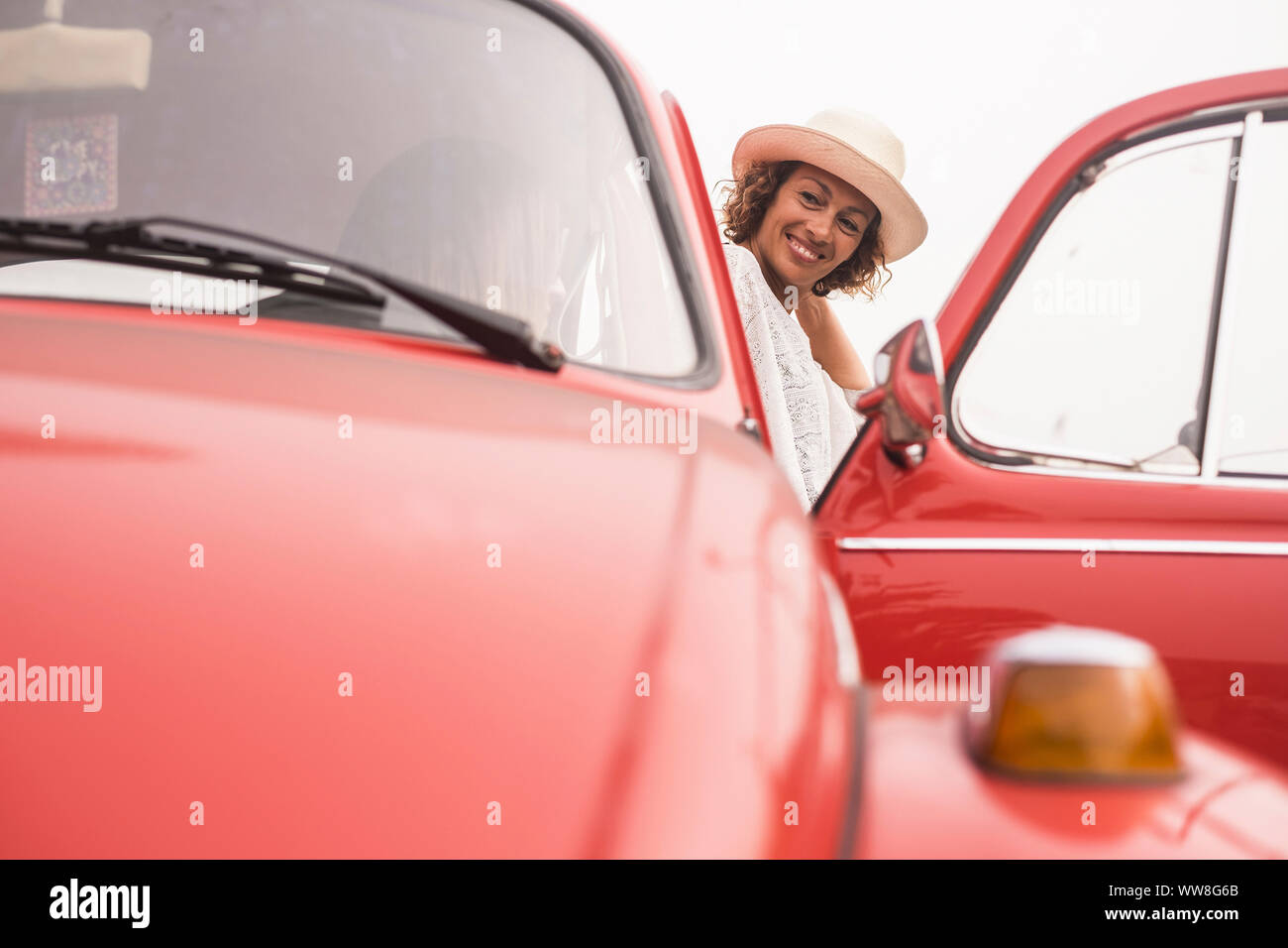Paar der kaukasischen mittleren Alter Frau in Outdoor Freizeitaktivitäten Aktivität in der Nähe von und sitzen auf einem roten Oldtimer bereit zu reisen, Stockfoto