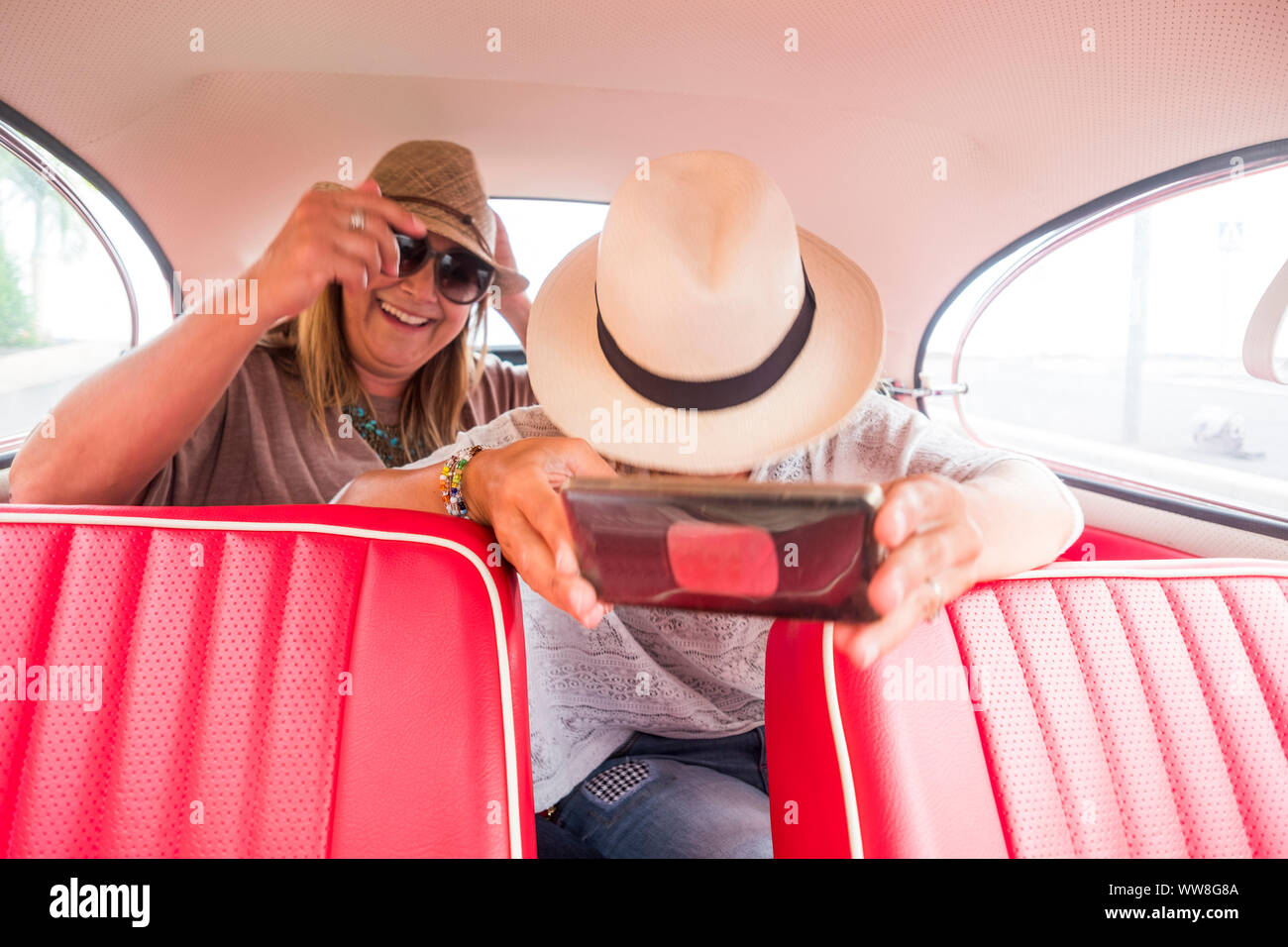 Freundliche Damen kaukasischen und selfie mit modernen smart phone in einem alten roten Oldtimer, moderne und alte Dinge, Internet und sozialen Netzwerken teilen Konzept Stockfoto