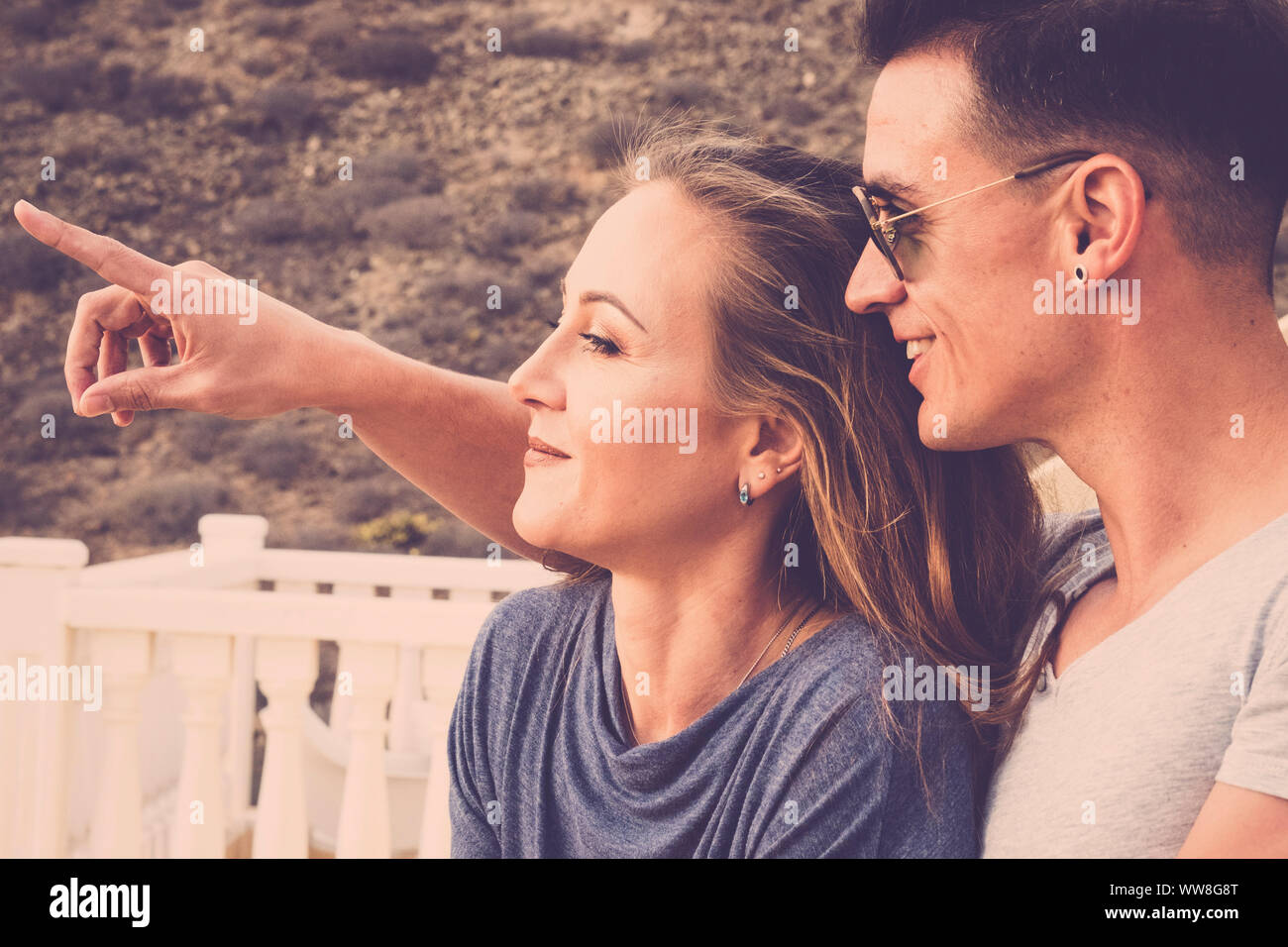Schön Schön kaukasischen Paar lächeln und schauen vor Ihnen, der junge Mann zeigen, die Dame etwas weit, Sommertag mit Sonnenlicht, Vintage Farben Filter, nette Leute im Freien auf der Terrasse Stockfoto