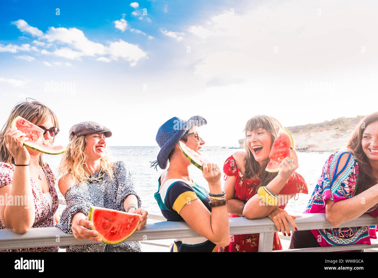 Blaue und rote Farben Bild der Gruppe der Frauen Freunde bleiben zusammen und haben Spaß im Sommer essen eine Wassermelone, Lächeln und Lachen, genießen Sie einen perfekten sonnigen Tag Urlaub Stockfoto