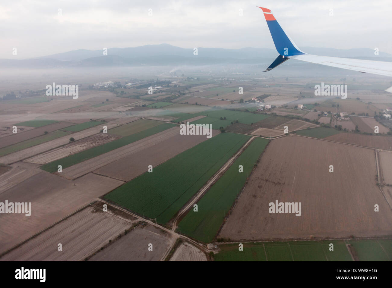 Vor der Landung dieser Wirbel Turbulenzen war sichtbar hinter der Tragfläche des Flugzeugs, Antenne mit dem Flugzeug Flügel und landwirtschaftlichen Flächen kurz vor der Landung am Flughafen Bodrum-Milas, Türkei, Stockfoto