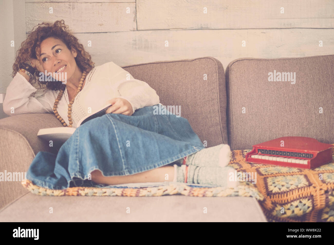 Schöne kaukasische Frau legte sich entspannt auf dem Sofa zu Hause sucht außerhalb des Fensters. kleine Pianobar Spielzeug zu ihren Füßen. Kreativität Gefühl für schöne Mädchen in Home Freizeit indoor Stockfoto